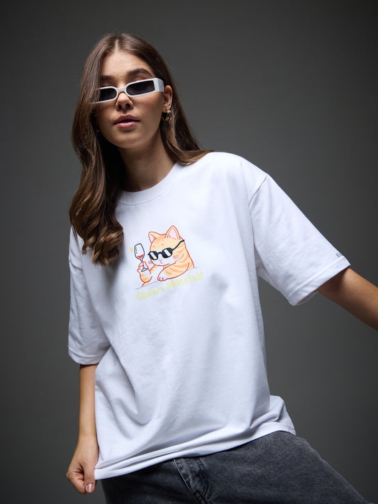 Female model wearing the white Joan Alvi Party Animals oversized T-shirt, front view with the colourful party-cat graphic
