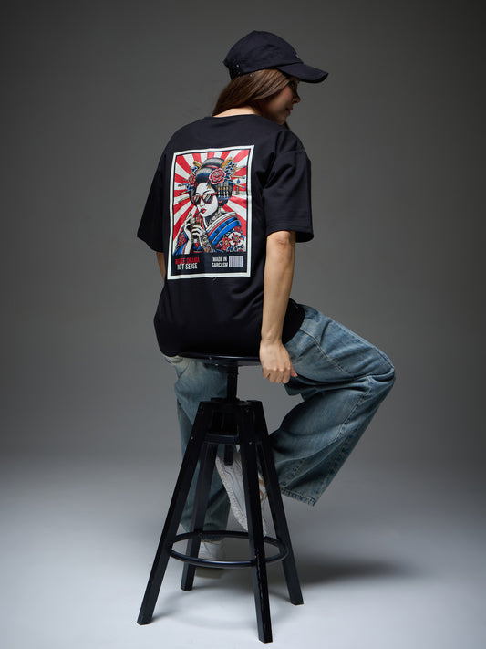 Female model seated in the black Joan Alvi Make Drama Not Sense oversized T-shirt, showing the geisha back artwork
