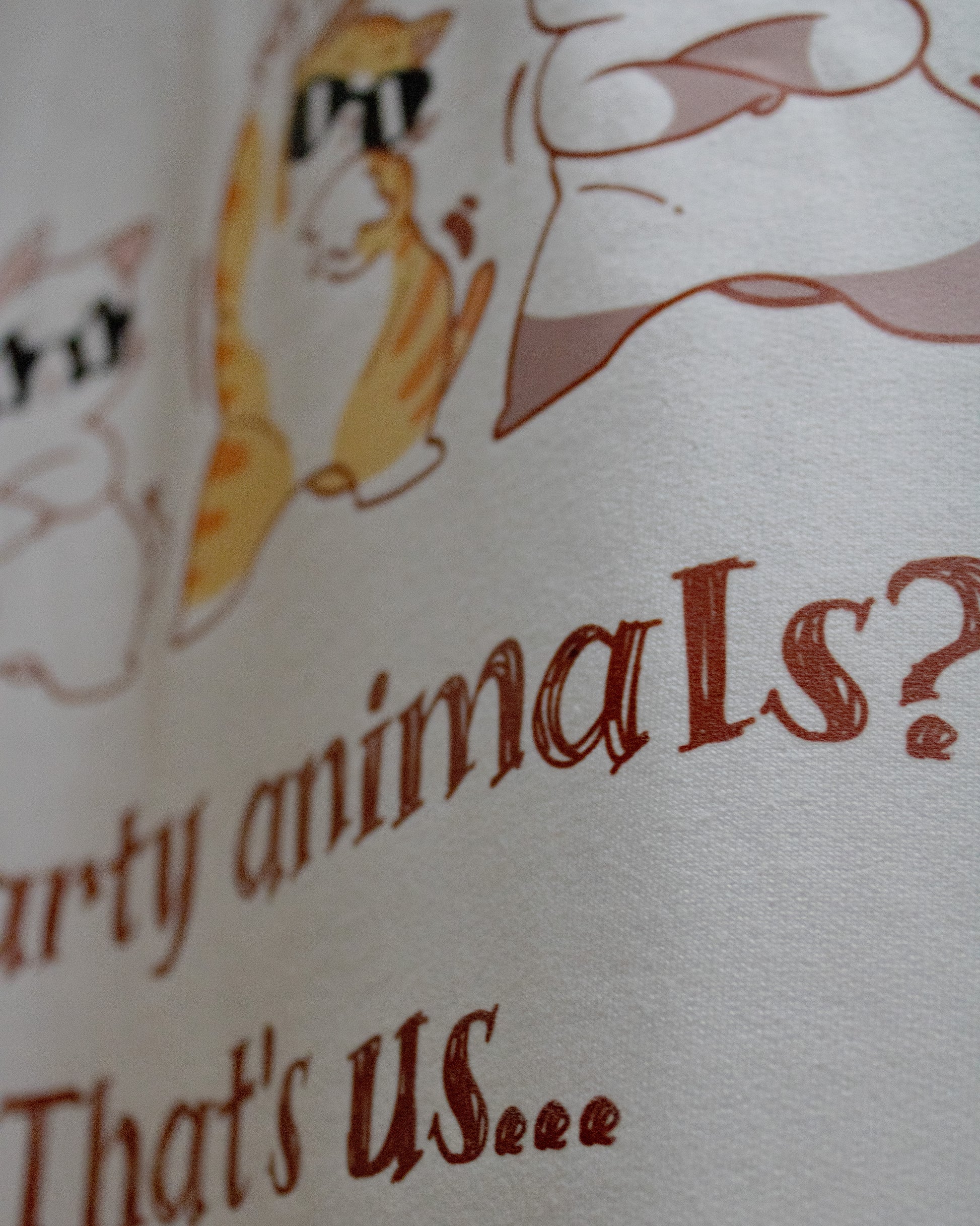 Extreme close-up view of a white premium French Terry cotton oversized t-shirt, focusing on the texture of the fabric and a high-quality graphic print on the back showing parts of dancing cartoon cats wearing sunglasses above the text "...rty animals? That's us...".